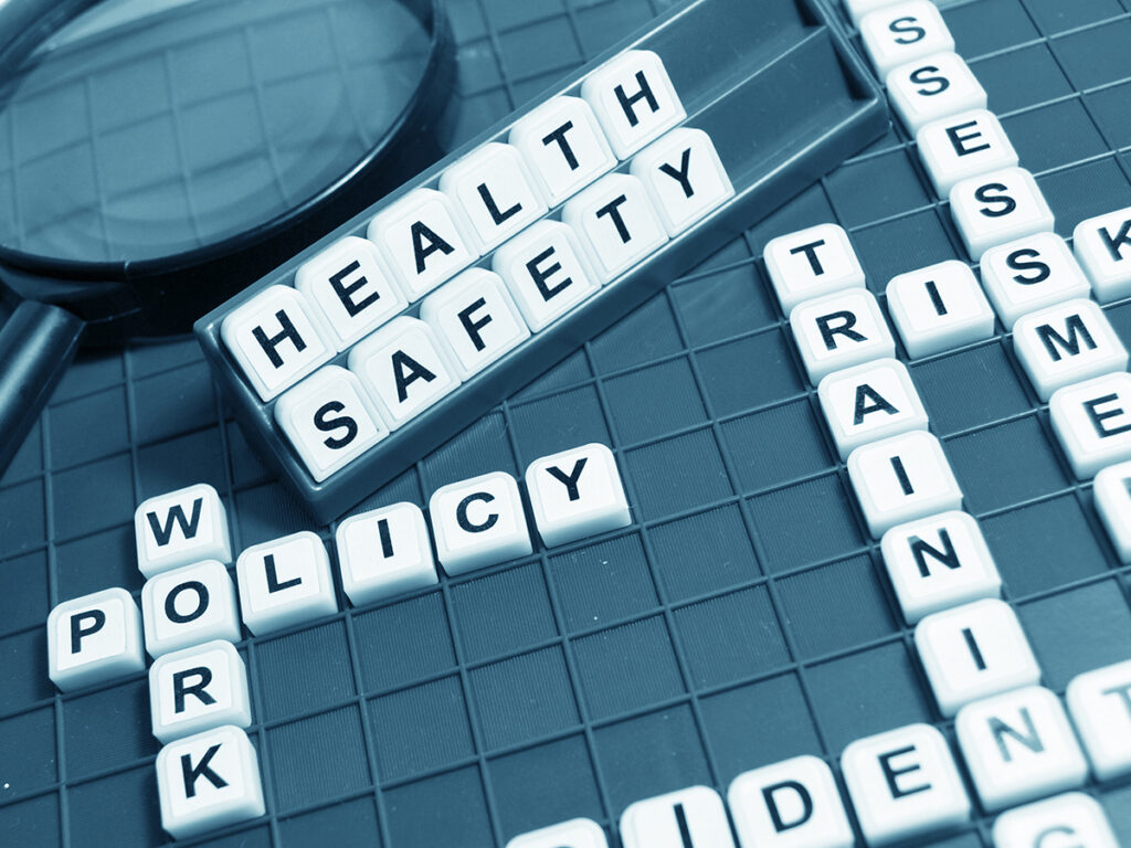 Word scramble game with white tile pieces that form the words safety, health, work, policy, accident, assessment, risk, and training